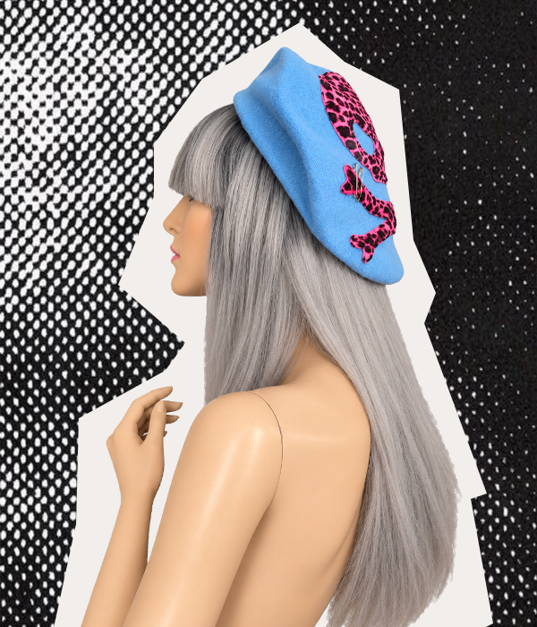 Side view of handmade baby blue skull beret with pink leopard-print appliqué on a silver-haired mannequin