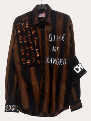 Men’s Seditionaries reproduction punk shirt with black and brown distressed stripes, slogan text, and armband detail hanging on a rail