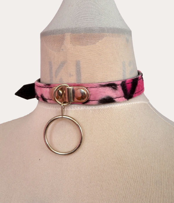 Pink and black leopard print adjustable punk collar on a mannequin, with silver-tone front O-ring detail and buckle fastening.