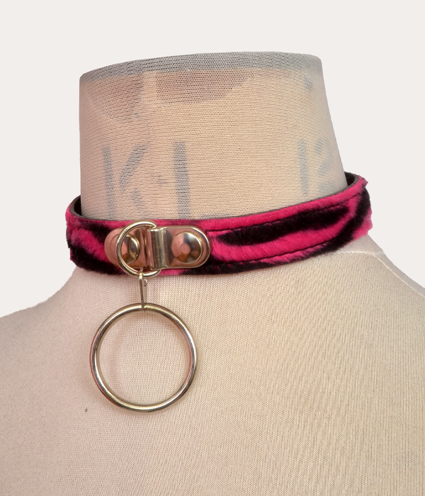 Pink and black zebra print adjustable punk collar on a mannequin, with silver-tone front O-ring detail and buckle fastening.