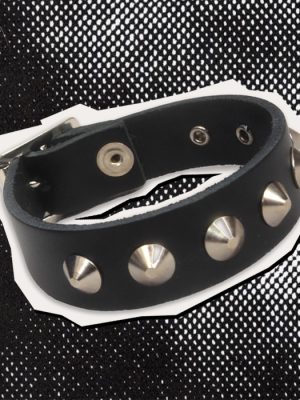 Black leather punk wrist cuff featuring five visible silver-coloured cone studs, adjustable metal eyelets and a metal buckle fastening. Photographed against a black and white halftone background.